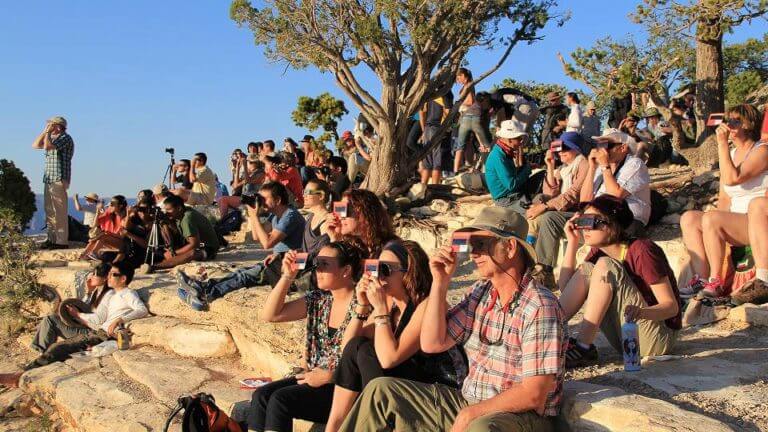 group of people watching the eclipse through special eye safety devices