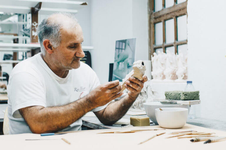 elderly man crafting small statues