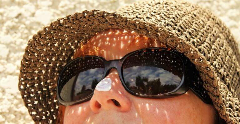 woman wearing sunglasses and a hat looking up